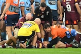 A male Queensland Maroons player receives medical attention during State of Origin III.