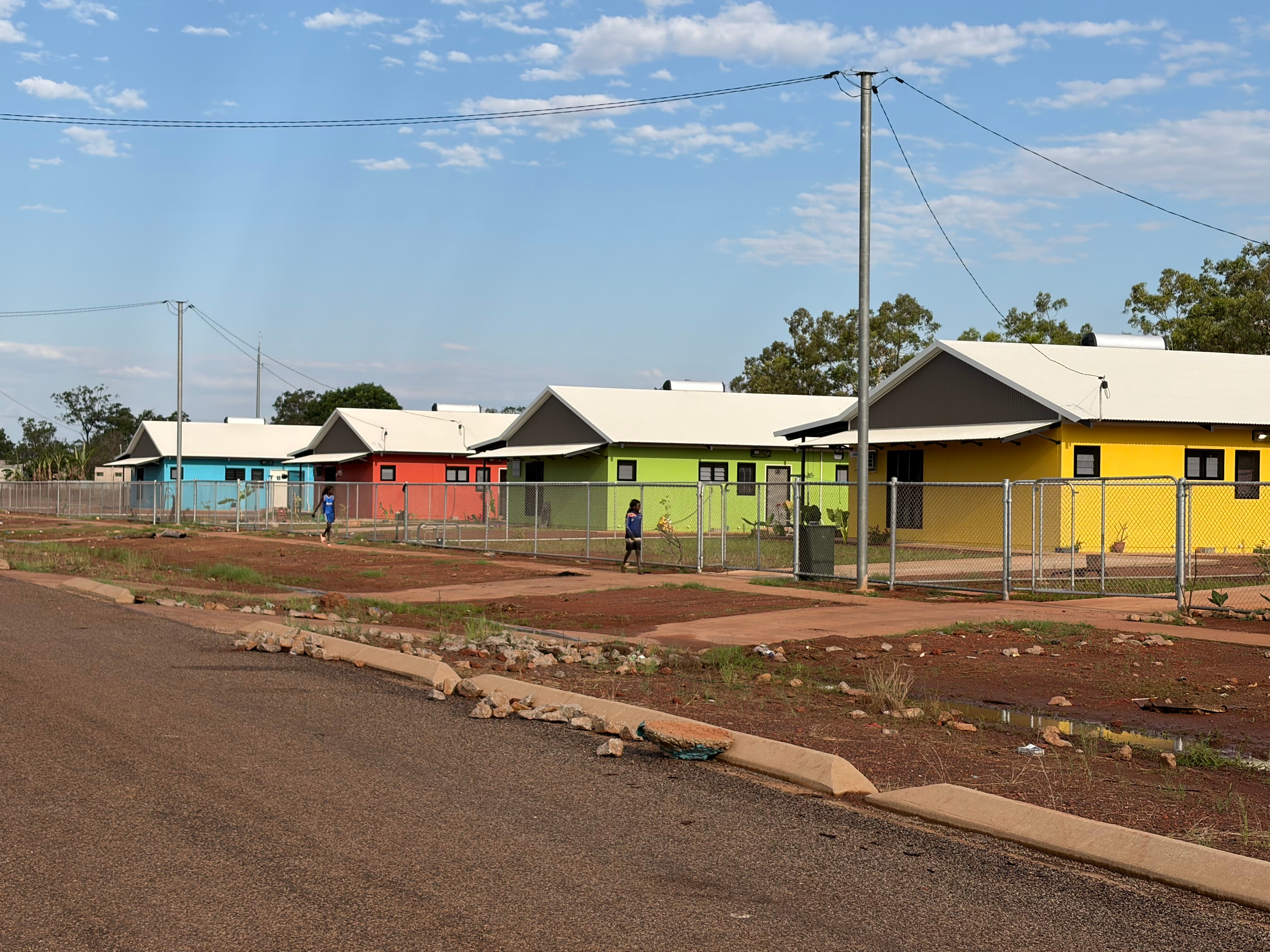 A street with a row of colourful houses behind wire fence