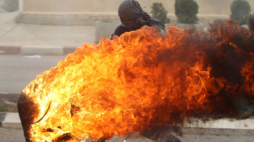 A Palestinian student pushes a burning tyre during clashes with Israeli soldiers in the Gaza Strip.