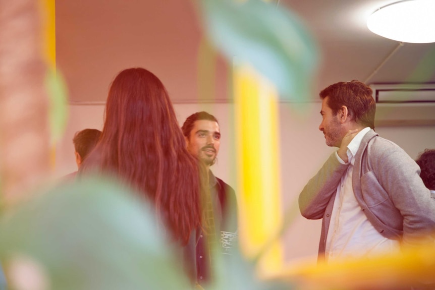 Three people in an office socialising.