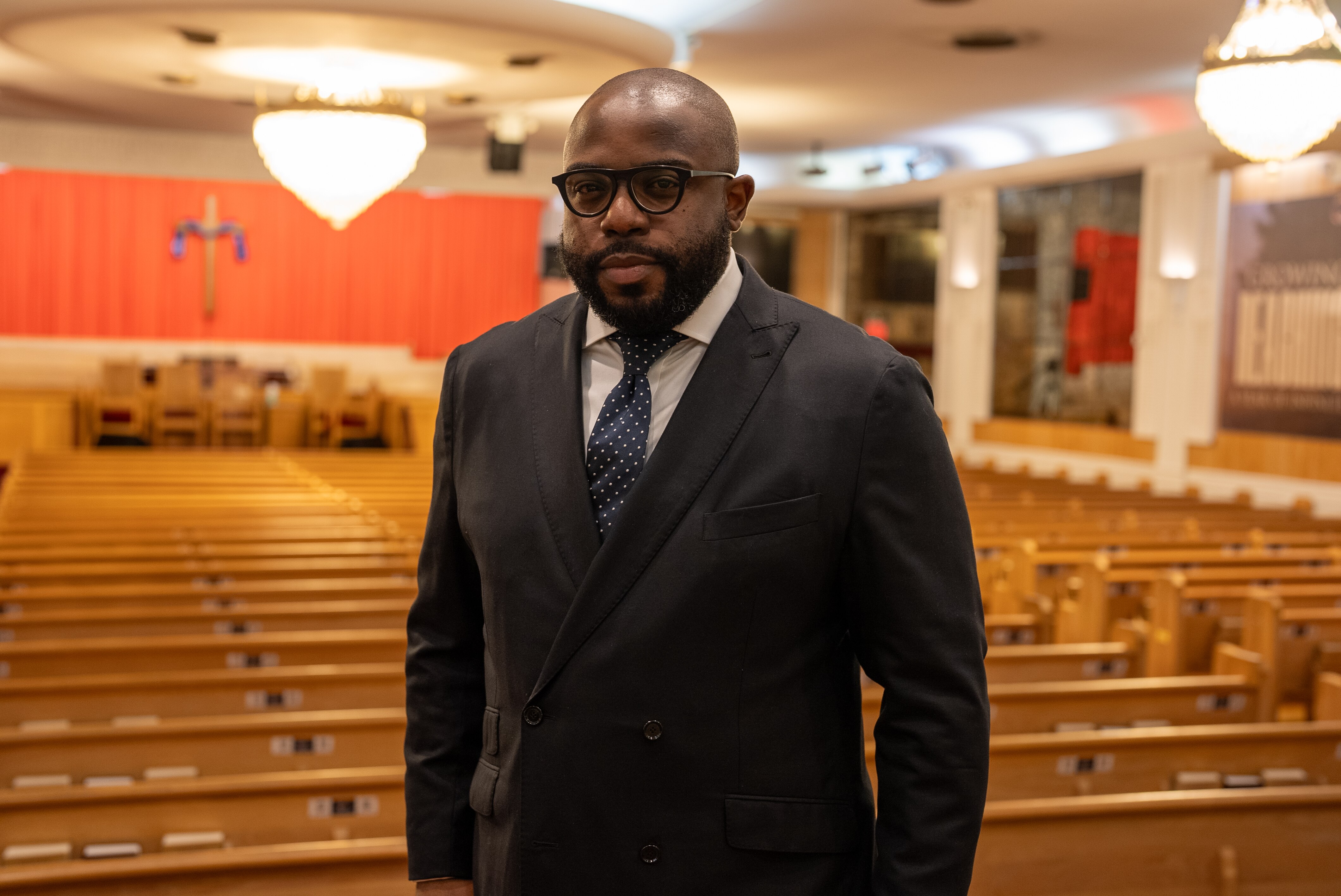A black man wearing a suit, standing in a church.