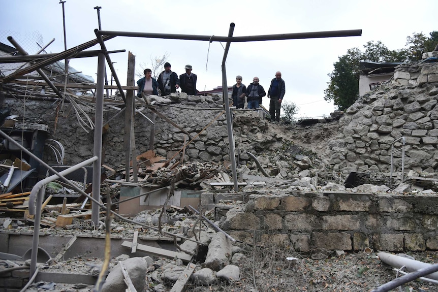 Men look at damage in a residential area after shelling by Azerbaijan's artillery.