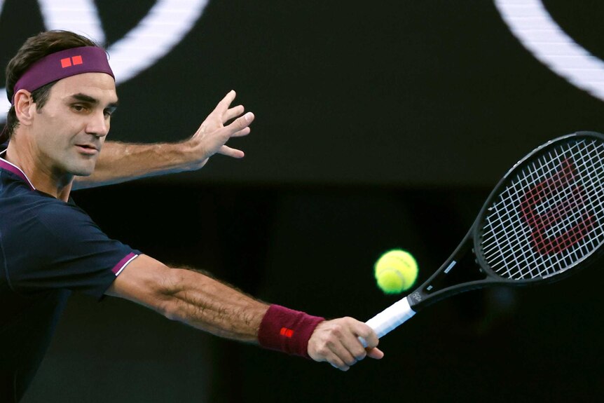 A tennis player wearing a headband leans into a shot as he plays a backhand at the Australian Open.