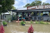 A family watches on from the deck of a business as food waters rise three meters