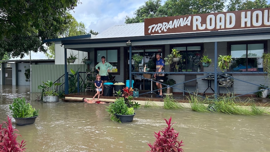 A family watches on from the deck of a business as food waters rise three meters