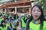 A woman in a high vis vest standing near a group of similarly dressed people. 