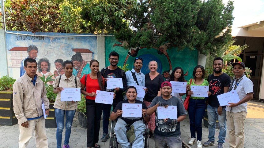 Twelve people in an outside area holding certificates.