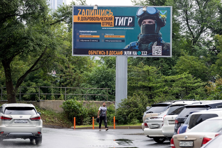 A large billboard on a street displays a Russian soldier. 