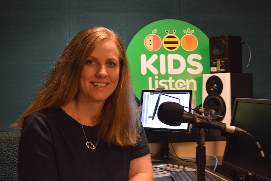 Stephanie Carrick in radio studio with green Kids Listen sign in background.
