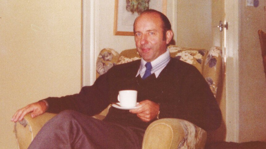 Donald Shearman sitting in a chair with a cup of tea in a house.