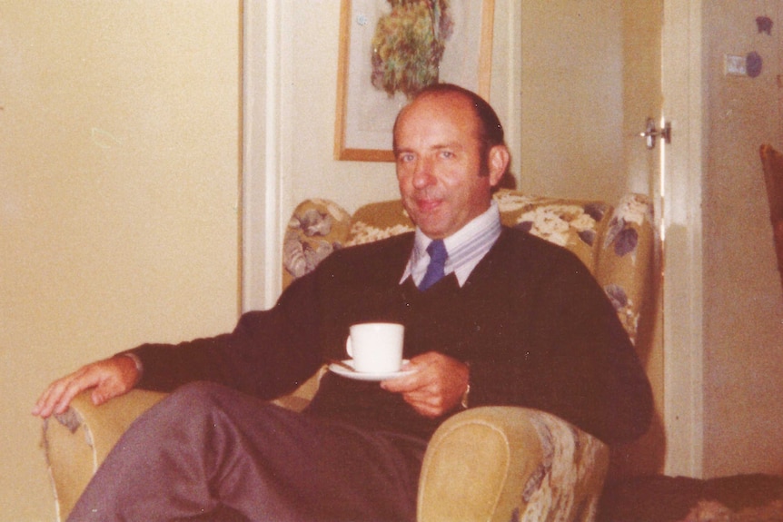 Donald Shearman sitting in a chair with a cup of tea in a house.