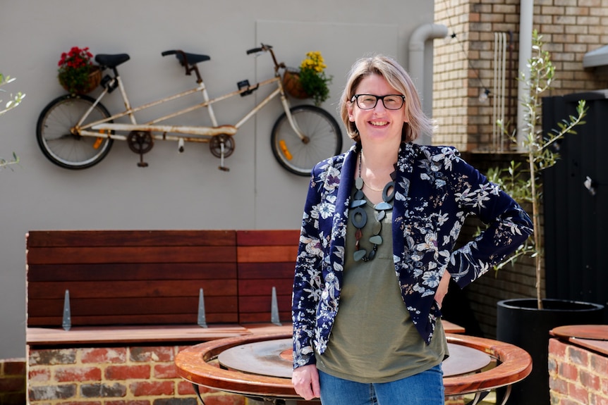 a woman smiling and standing in front of a bike on the wall