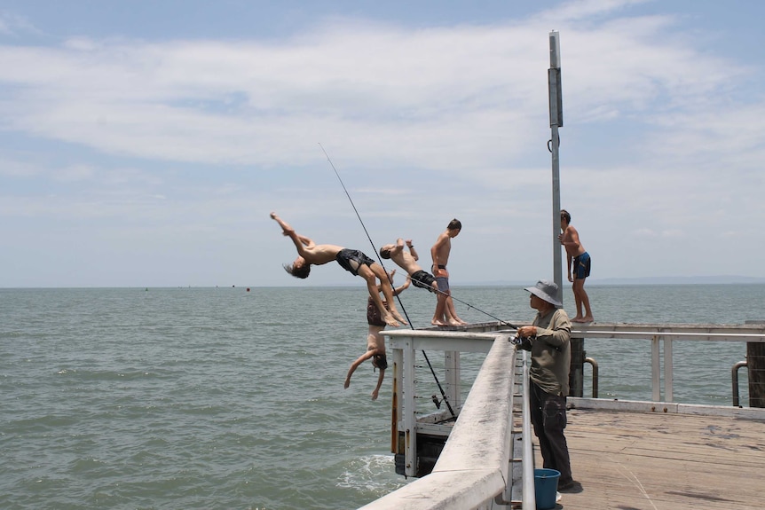 People jump off a jetty