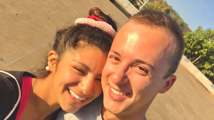 A young dark-haired woman and a fair-haired man in a t-shirt hug and smile in a selfie portrait