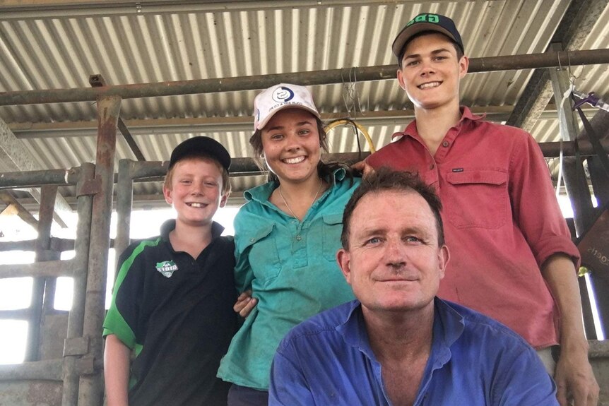 A family standing inside a roofed cattle pen