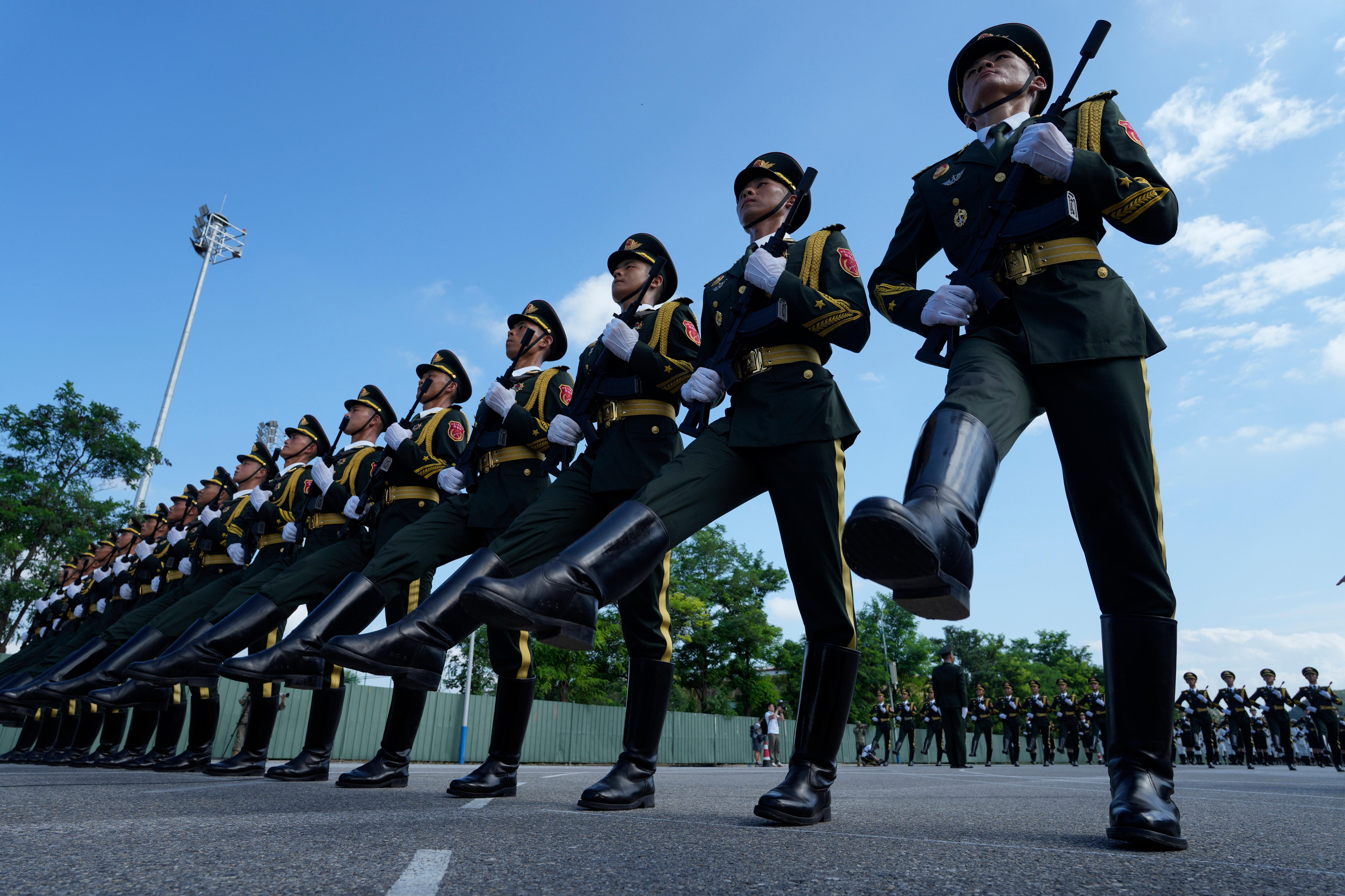 Chinese soldiers in green, gold and white dress uniform march with rifles as a rehersal for a massive military parade.