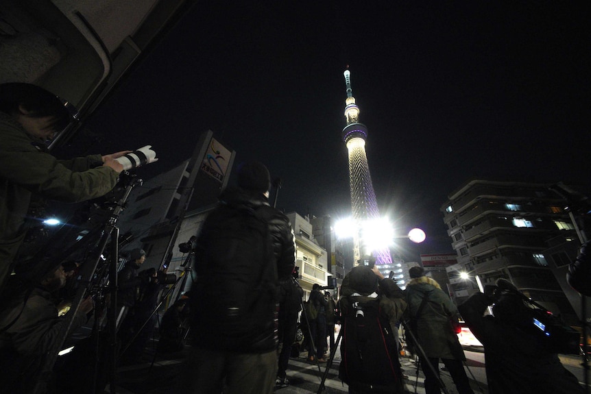 People photograph lunar eclipse seen over Tokyo Skytree in Tokyo.