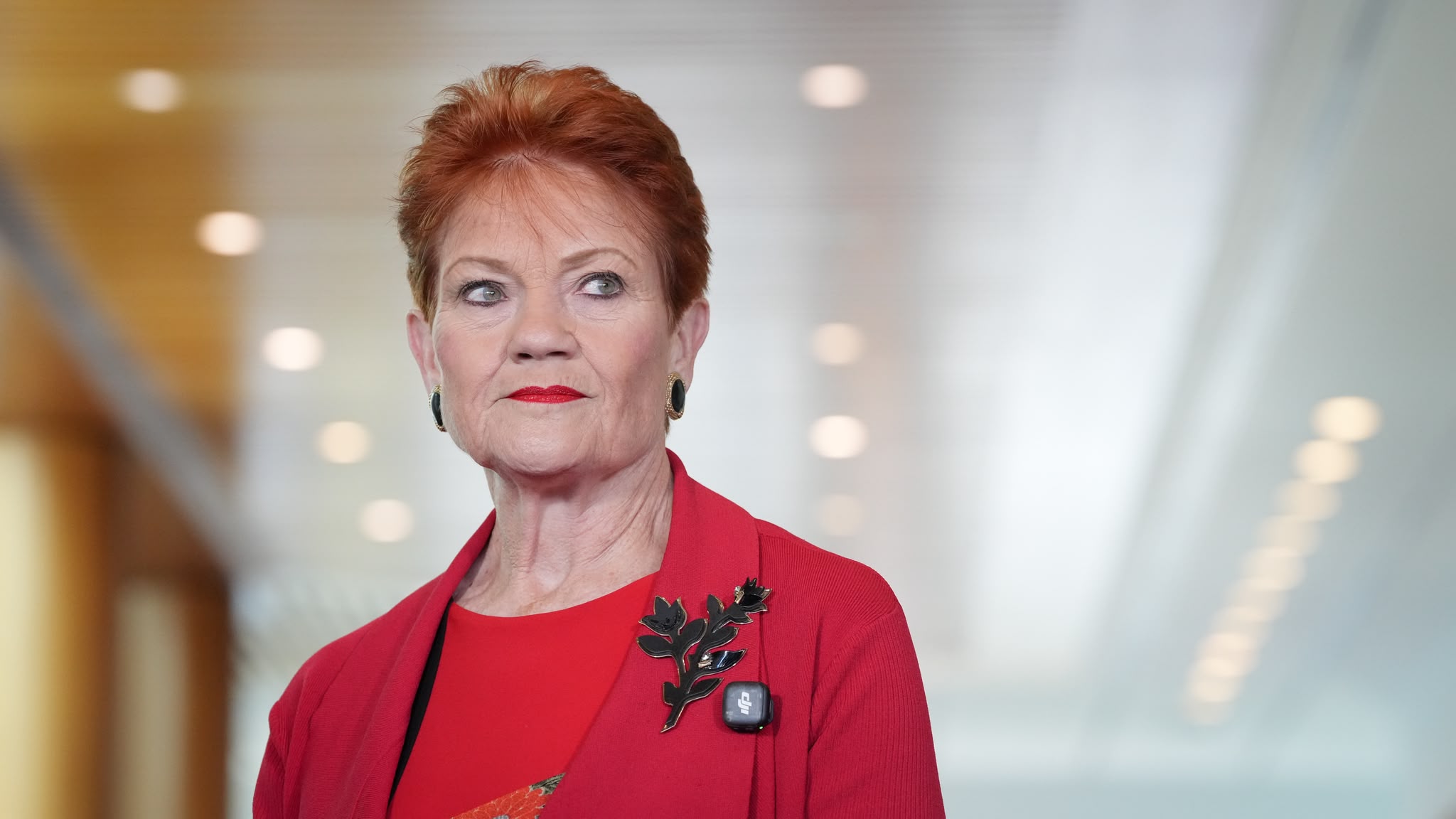 Pauline Hanson in a red jacket looks serious at Parliament House.