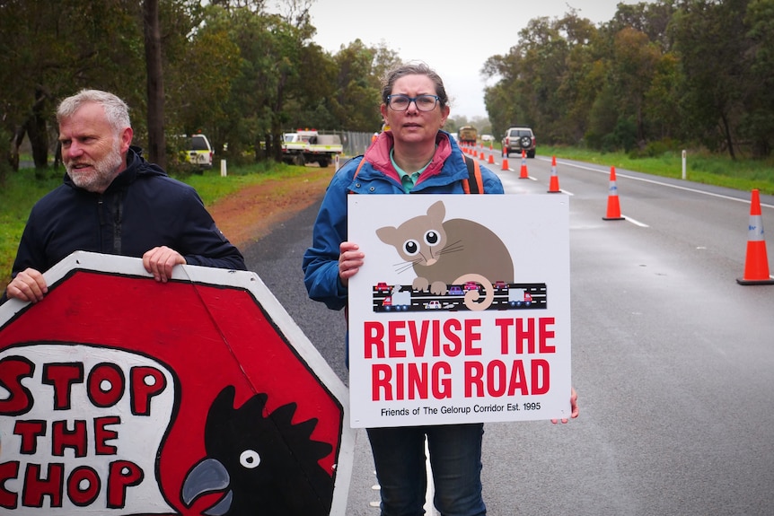 People stand on a road holding placards