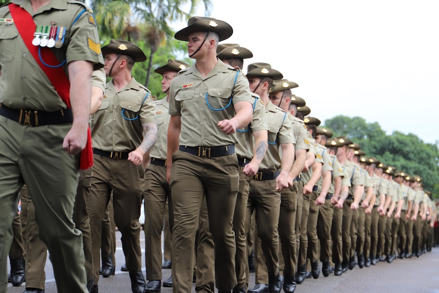 Men in army uniform and slouch hats march in formation.