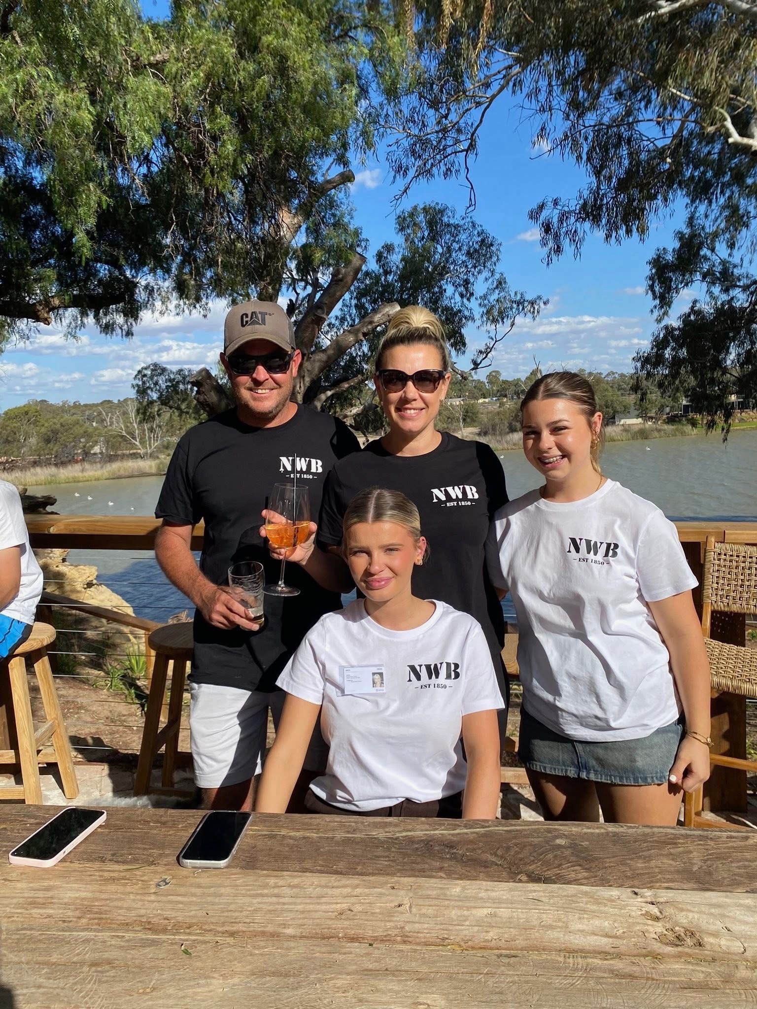 Un hombre, una mujer y dos adolescentes sonríen a la cámara. Hay un río detrás de ellos. 