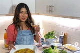 A woman wearing a denim apron holding a tray of food