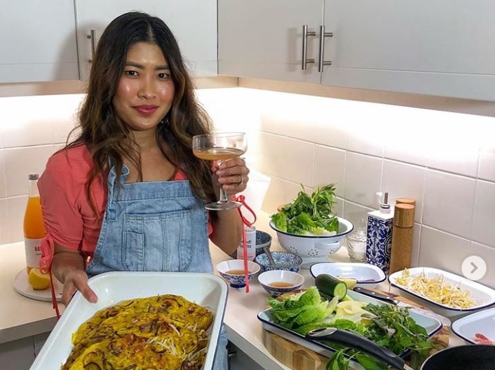 A woman wearing a denim apron holding a tray of food