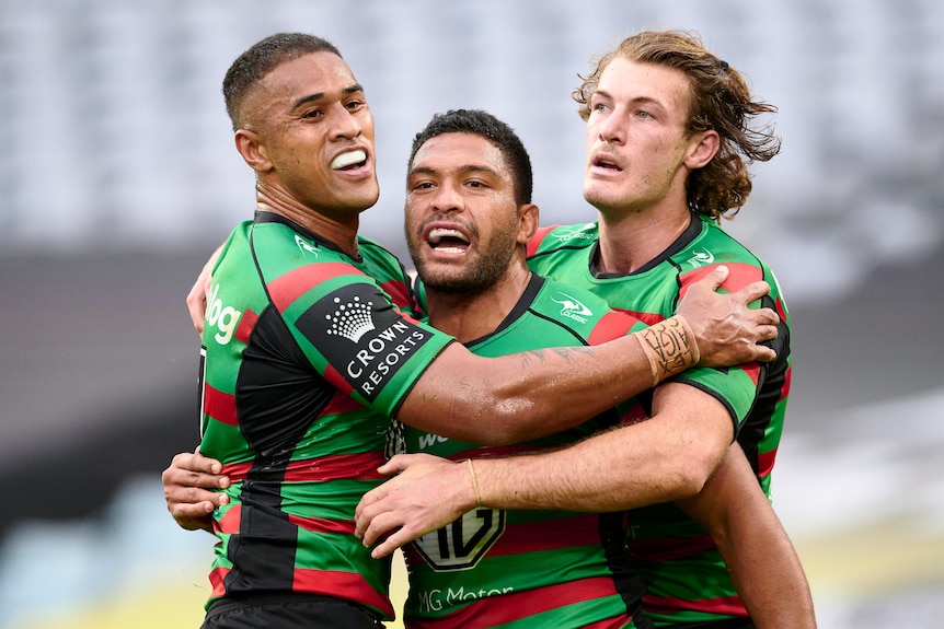 Taane Milne is hugged by two teammates on either side of him