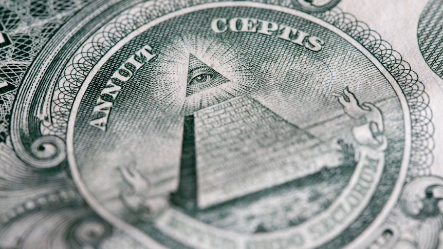 A close up shot of the reverse side of an American one dollar bill depicting a pyramid with 13 steps and the Eye of Providence