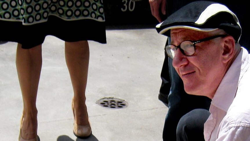 Actor Geoffrey Rush crouches next to his plaque on Theatre Walk