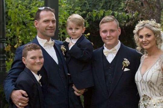 A man and three boys and a woman wearing a wedding gown