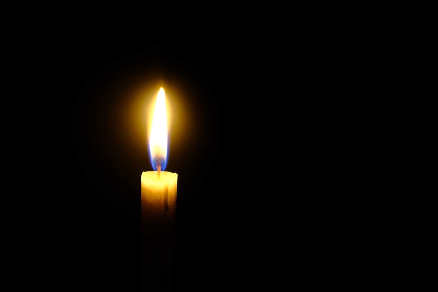 A candle flame burning against a black background.