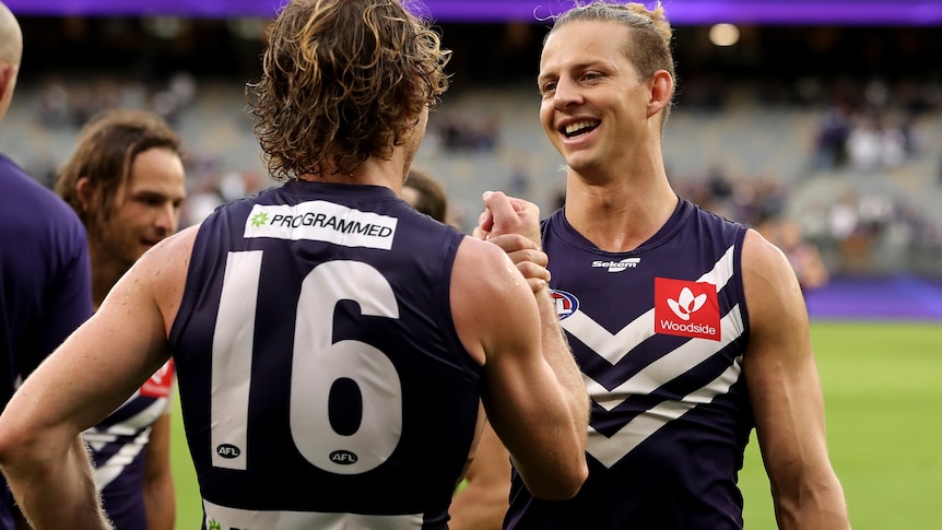 Nat Fyfe smiles while high-fiving David Mundy, whose back is to camera