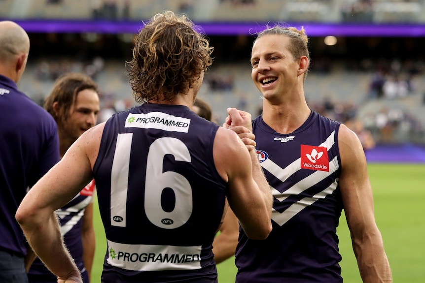 Nat Fyfe smiles while high-fiving David Mundy, whose back is to camera