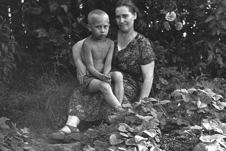 An old photo of Vladimir Putin as a child with his mother in a field