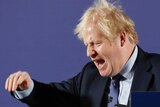 Boris Johnson gestures with his eyes closed in front of a lectern with words 'unleashing Britain's potential'.