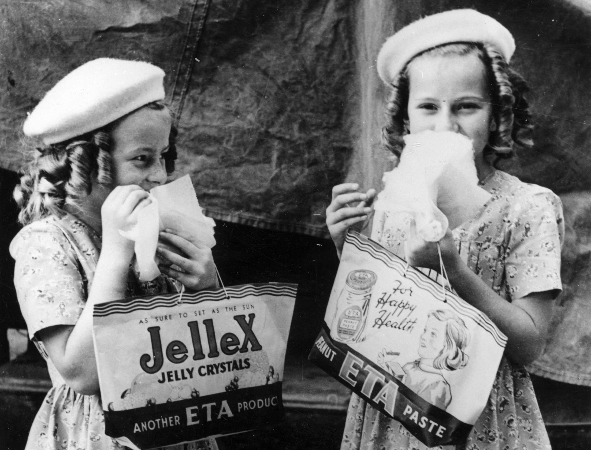 Black and white photo of two young girls holding showbags.