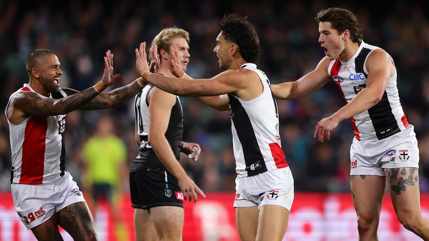 Two St Kilda players high five in celebration after a goal.