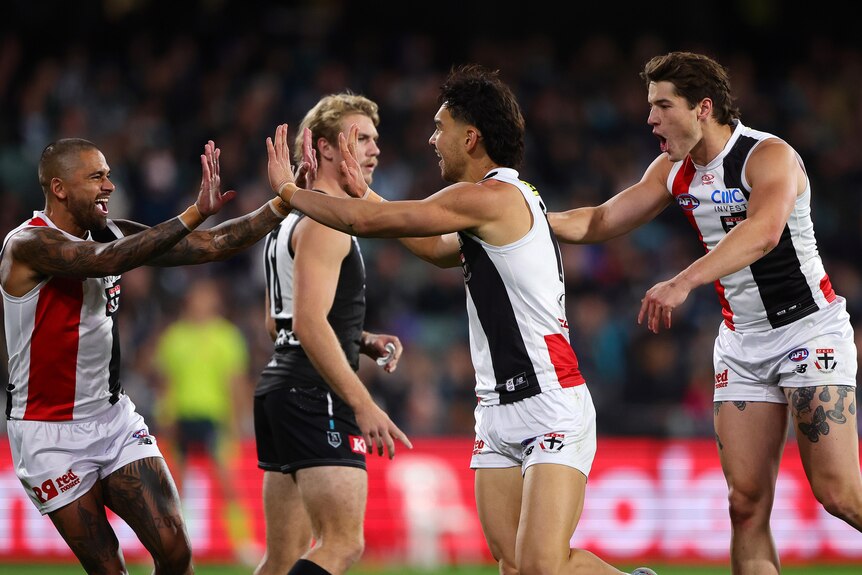 Two St Kilda players high five in celebration after a goal.