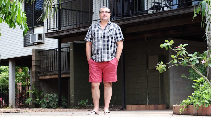 A man stands outside a house.