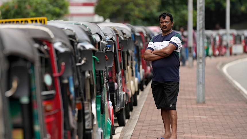 An autorickshaw driver waits in a queue hoping to get fuel
