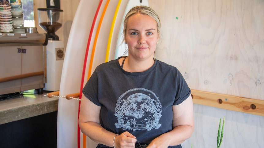 A woman standing in front of a wall of surfboards.