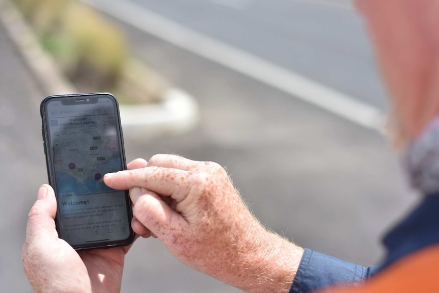 A person holds a phone open on a "welcome!" page with a map of the Green Triangle region.