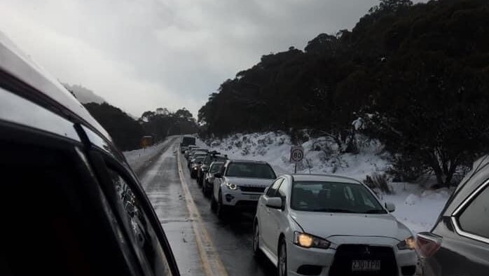 A line of cars queue up to the Thredbo ski fields. The queue extends along the highway and around the bend