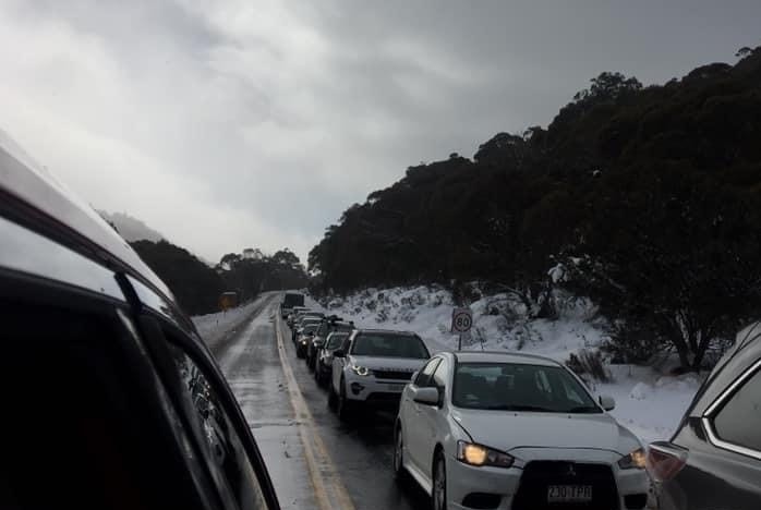 A line of cars queue up to the Thredbo ski fields. The queue extends along the highway and around the bend