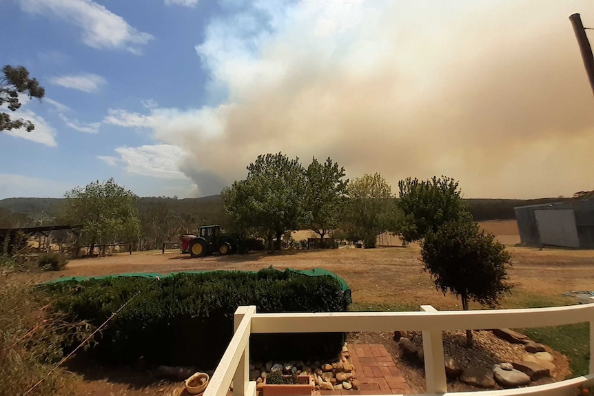 A cloud of orange-white smoke is seen from a farm.