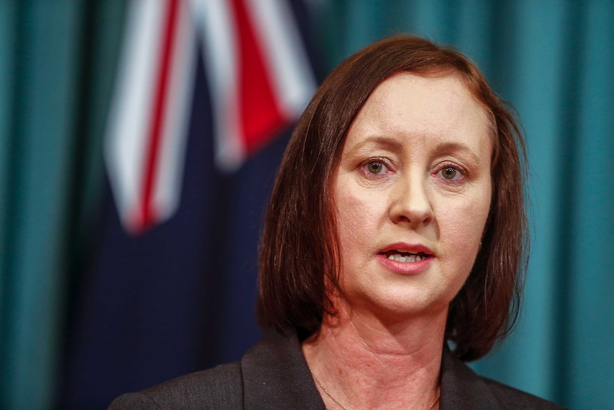 Yvette D'Ath stands in front of an Australian flag.