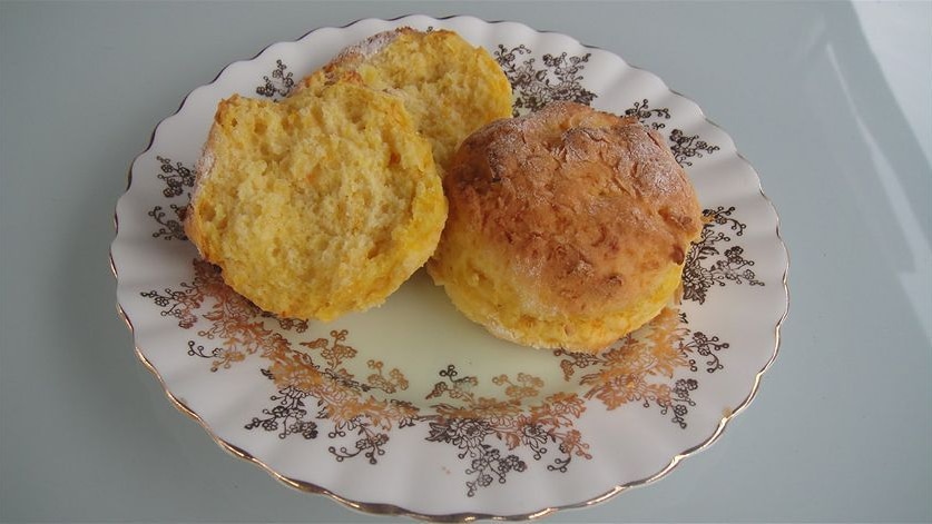Two scones, one split in half, on a small fancy plate.