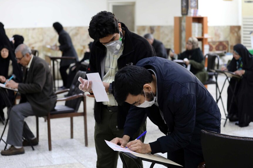 Voters with face masks fill out their ballots in the parliamentary elections at a polling station.