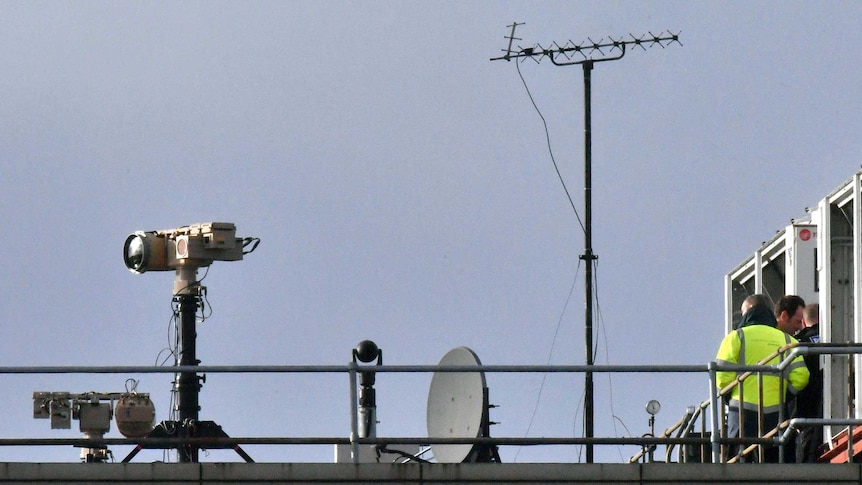 Technical equipment on a roof is silhouetted against the sky.